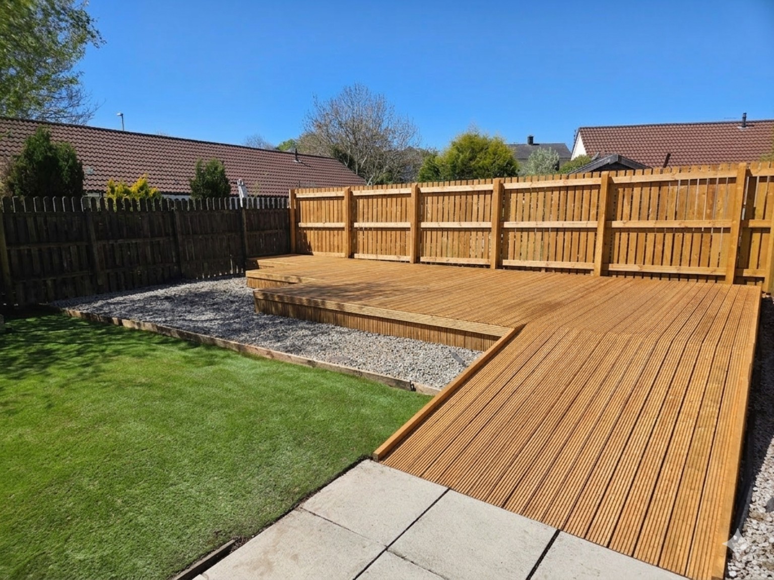 Tidy garden with timber decking, fencing, lawn and gravel borders